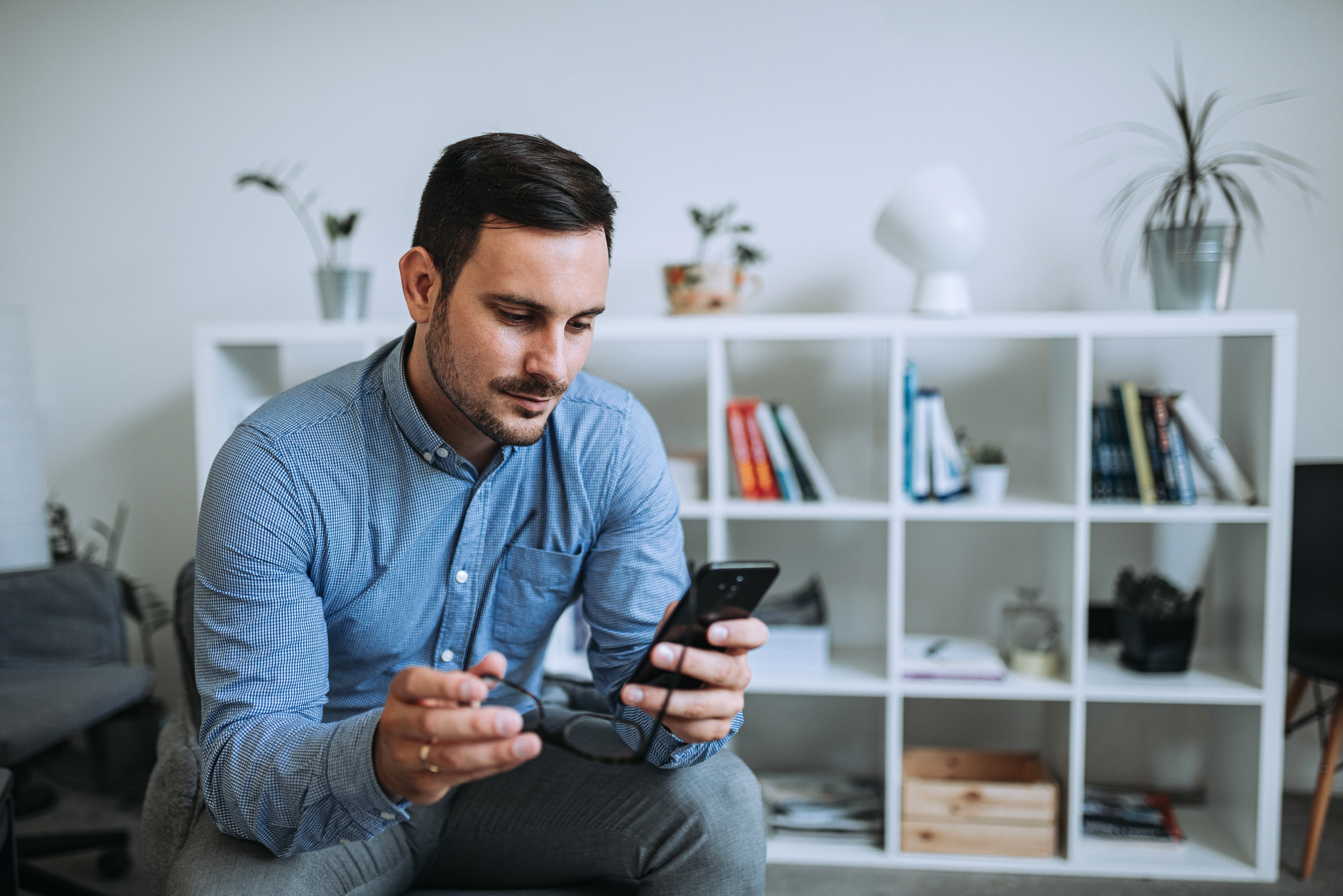 Hombre mirando el smartphone en vivienda VPO Hombre mirando smartphone en vivienda VPO